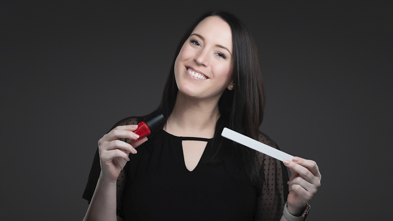 Woman smiling and holding a red apple and a white test strip against a dark background