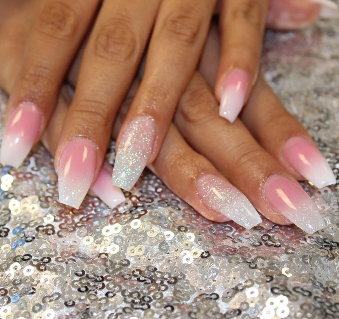 Hands with pink ombré and glitter nails resting on a silver sequin surface