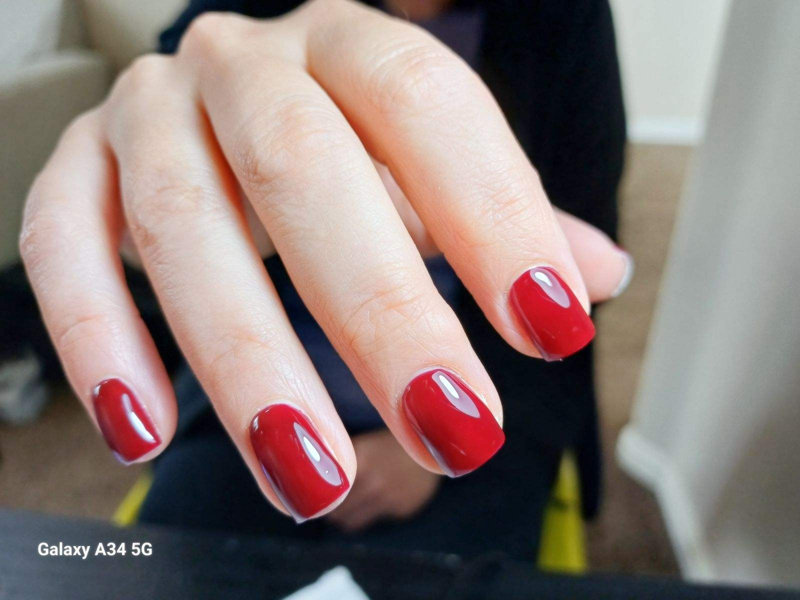 Hand with glossy red manicured nails held close to the camera