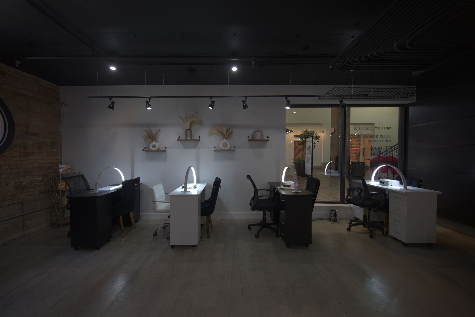 Dim nail salon with manicure stations, task lamps, and chairs along the back wall