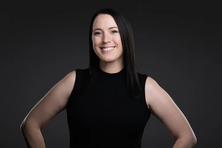 Smiling person in a black sleeveless top against a dark gray background