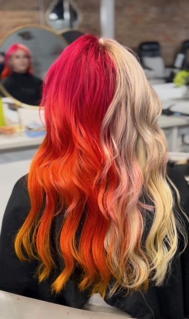 Long wavy hair dyed bright red, orange, and blonde, viewed from the back in a salon chair