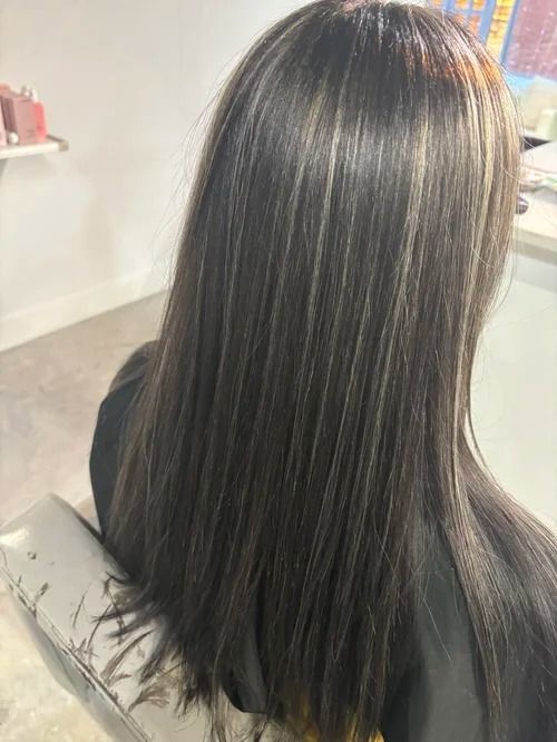 Straight dark hair with subtle highlights, viewed from behind in a salon chair.