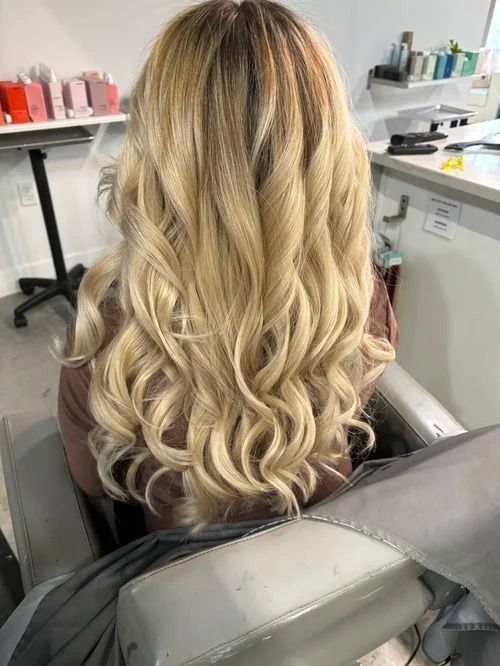 Long wavy blonde hair viewed from behind in a salon chair