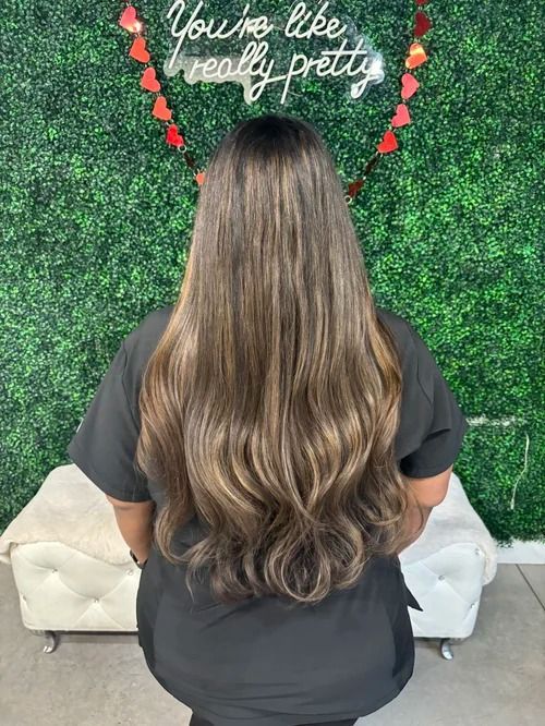 Woman with long wavy hair facing a green wall sign reading “You’re like really pretty”