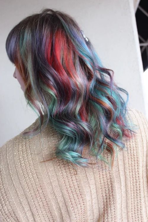 Shoulder-length wavy hair with teal, pink, and purple highlights over a beige sweater