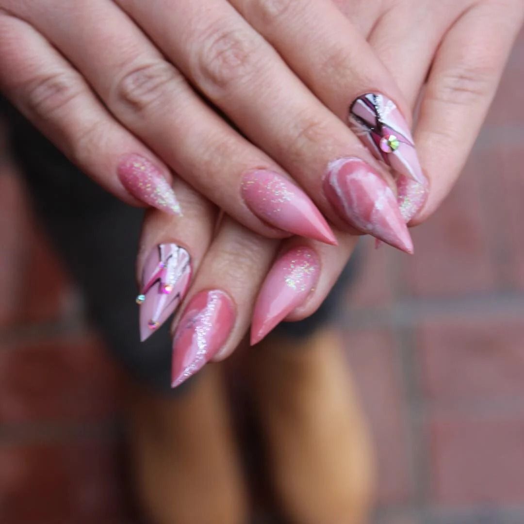 Hands with long pink manicured nails and delicate floral nail art over a blurred background