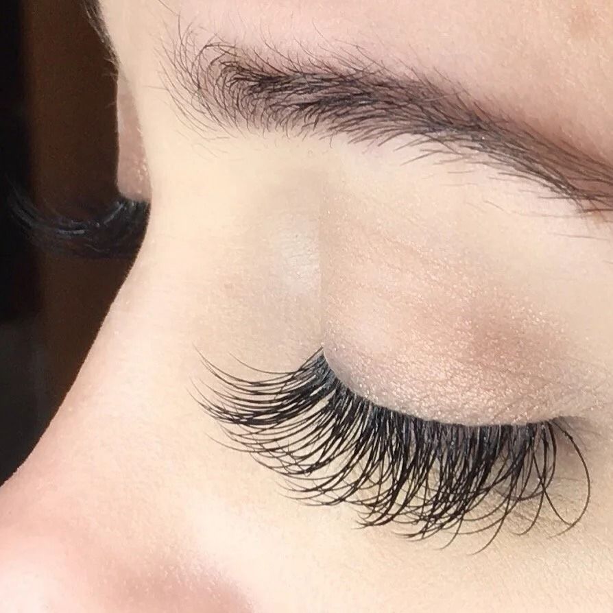 Close-up of a closed eye with long, curled black eyelashes and natural makeup