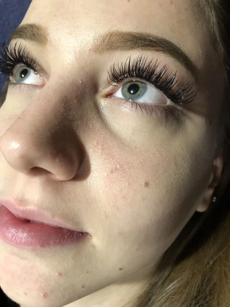 Close-up of a person looking upward, with long eyelashes and natural makeup.
