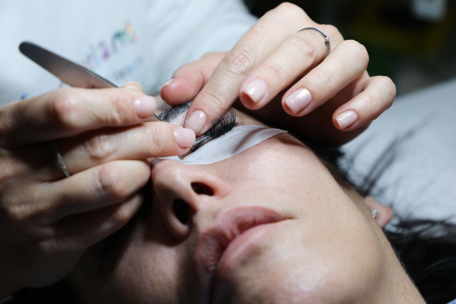 Gloved hands apply a skincare serum to a woman's forehead during a facial treatment