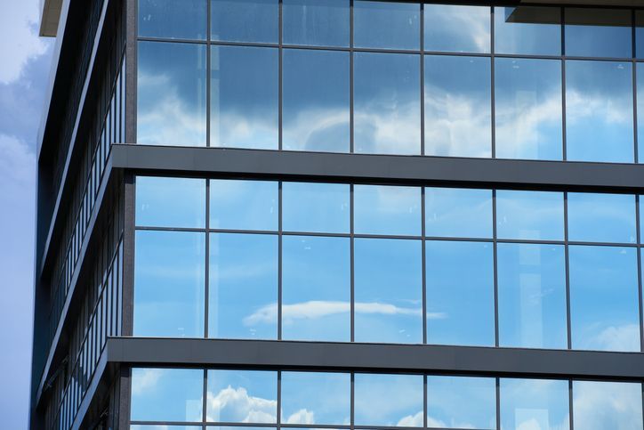 Facade of a modern building on a bright Sunny day, blue sky and clouds reflecting in a glass, beautiful exterior of the new building