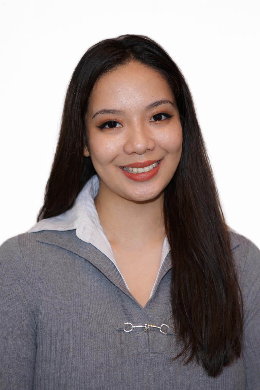 Smiling person with long dark hair wearing a gray sweater on a white background