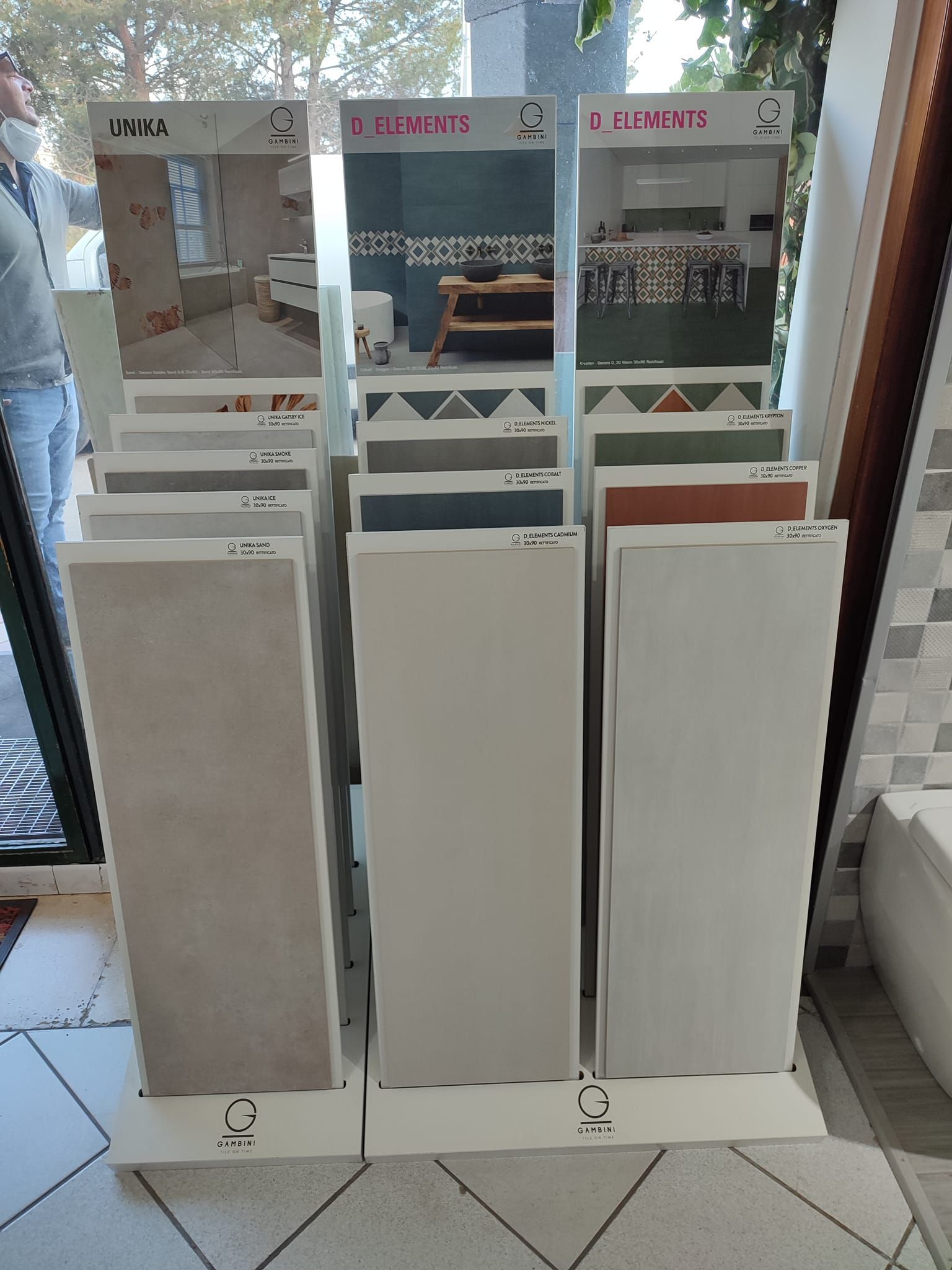 Un'esposizione di piastrelle in un negozio con un uomo in piedi sullo sfondo.