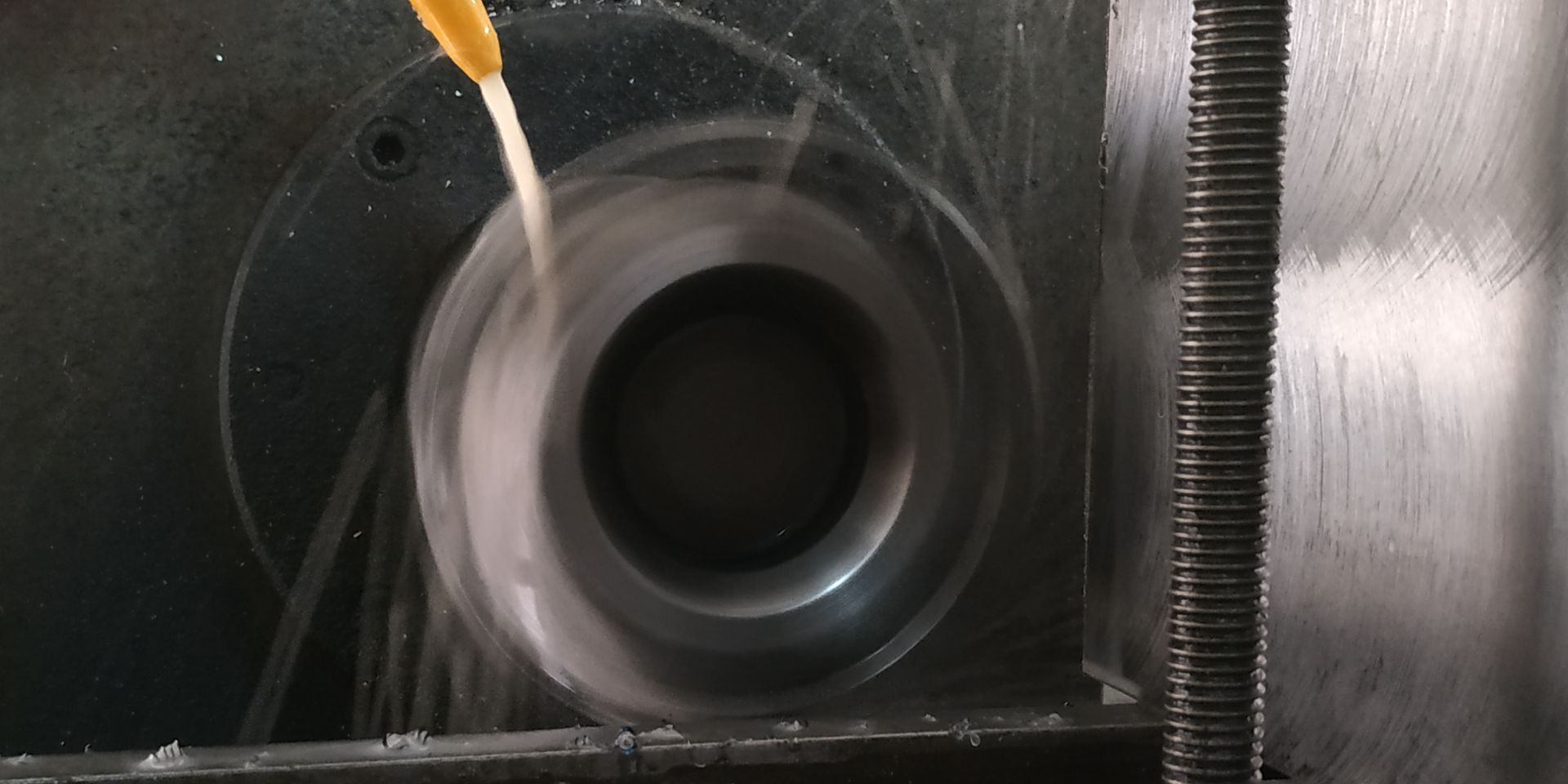 Una fresatrice CNC taglia un pezzo di metallo su un banco da lavoro, con tubi del liquido di raffreddamento blu sopra.