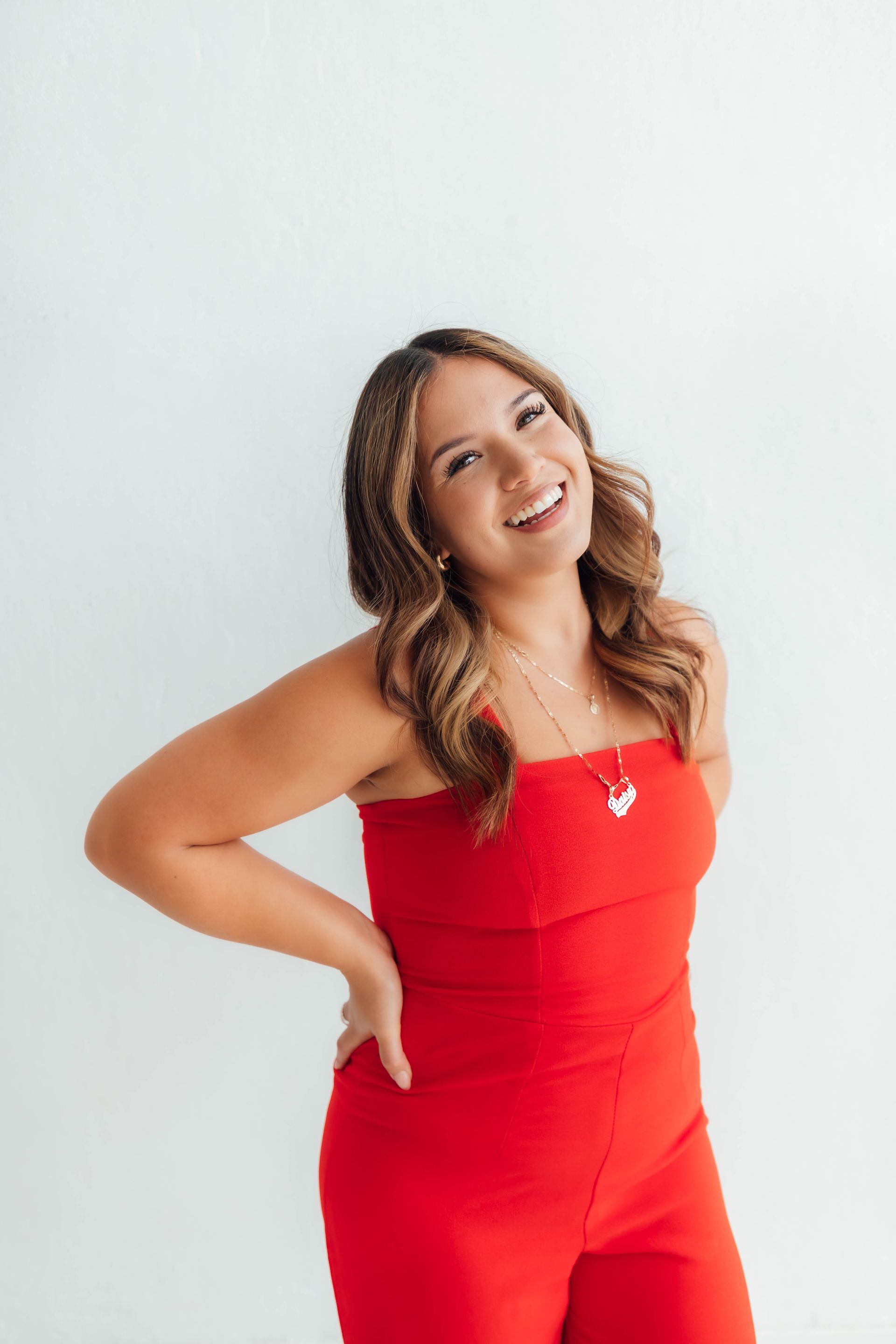 Woman in a red outfit smiling against a white background