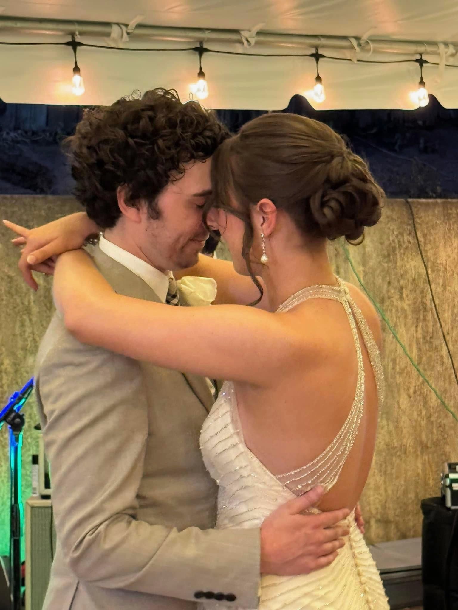 Two people in formal attire embracing and smiling at a wedding reception