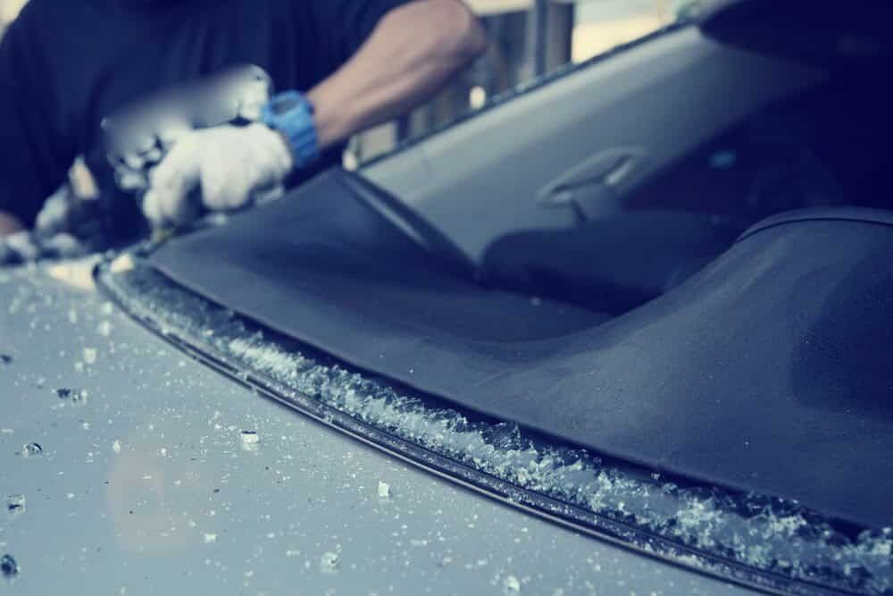 A Man is Cleaning the Windshield of a Car With a Brush — Shepparton Radiators & Windscreens in Echuca, VIC