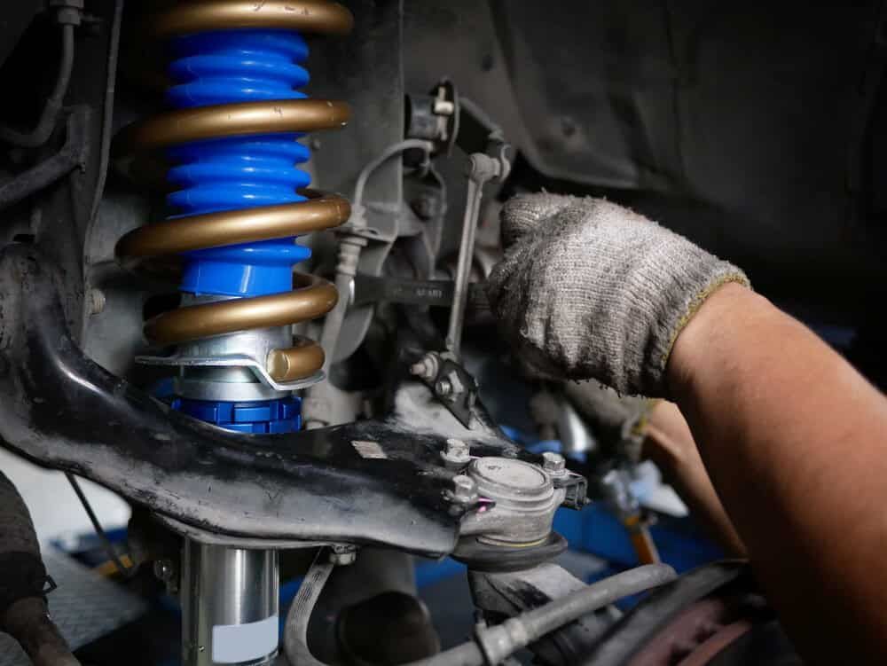 A Person is Working on a Shock Absorber on a Car — Shepparton Radiators & Windscreens in Yarrawonga, VIC