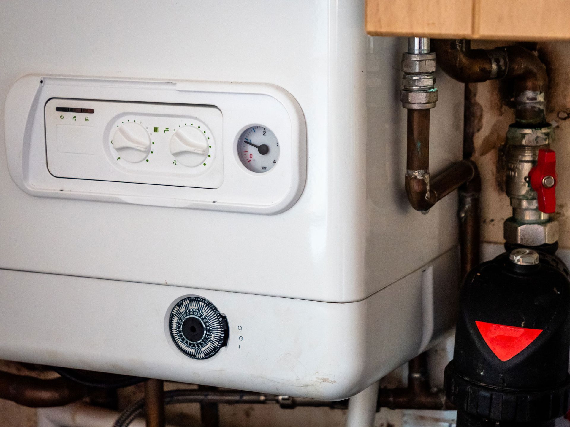 A close up of a white boiler with pipes attached to it.