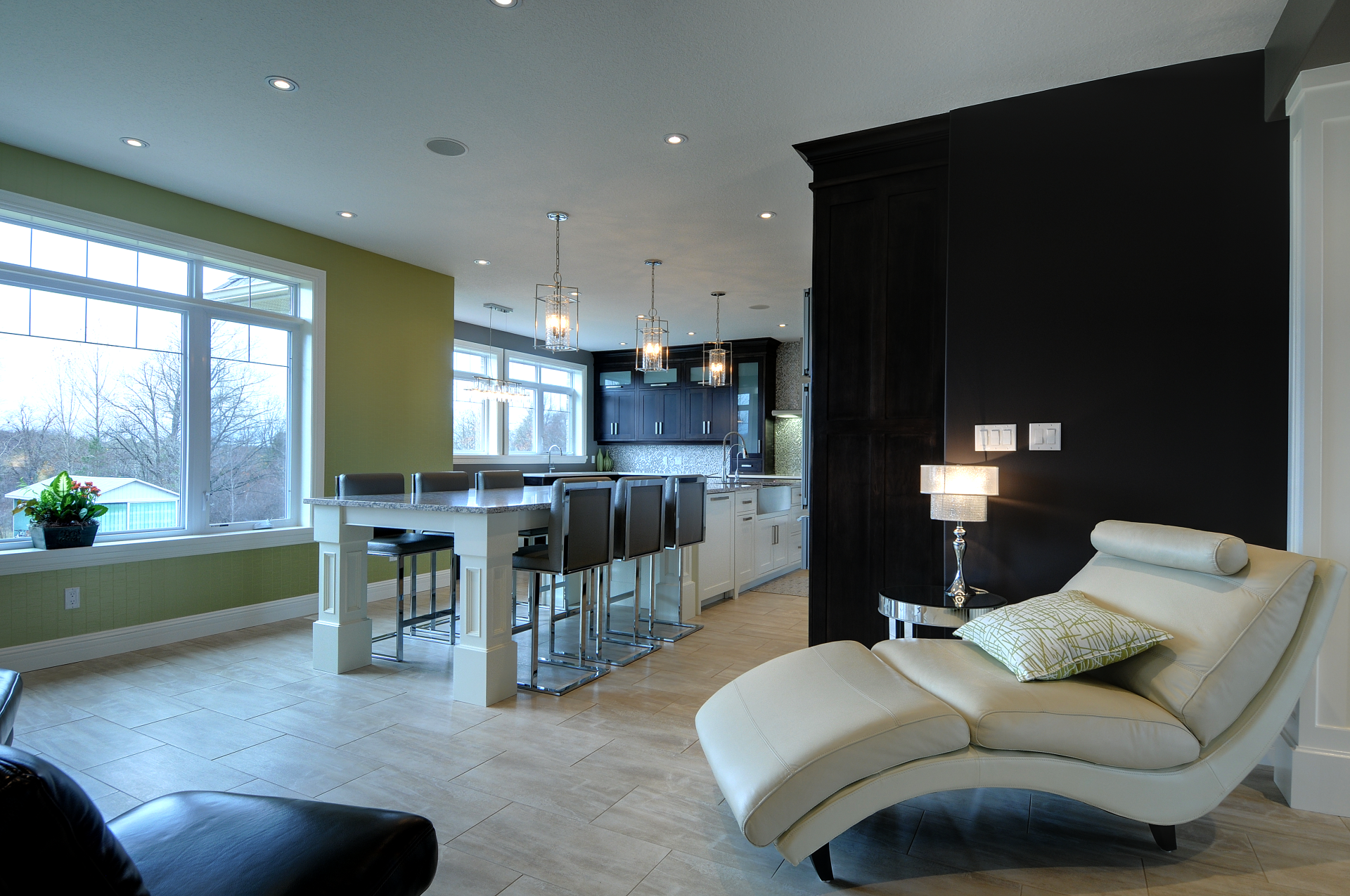 A living room with a chaise lounge and a kitchen in the background