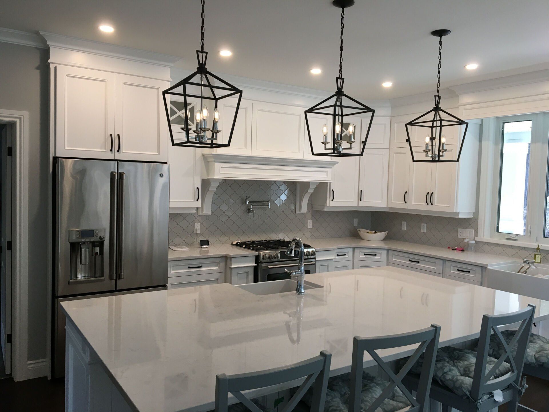 A kitchen with white cabinets and stainless steel appliances and a large island.