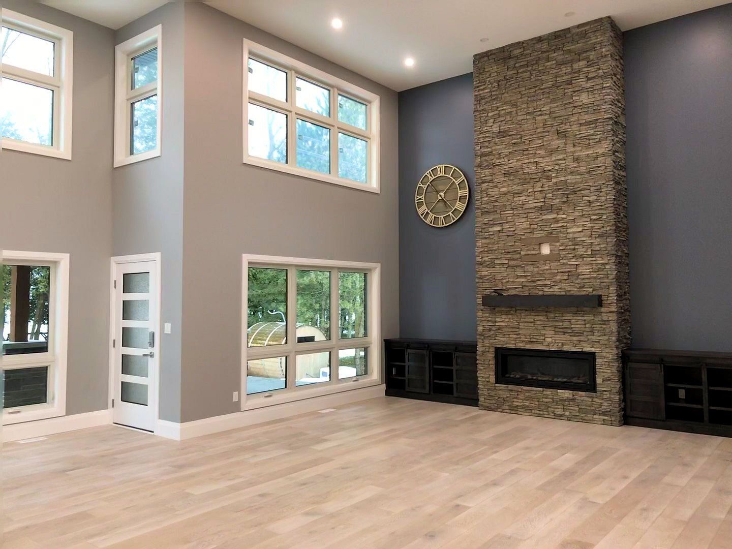 An empty living room with a fireplace and a clock on the wall.