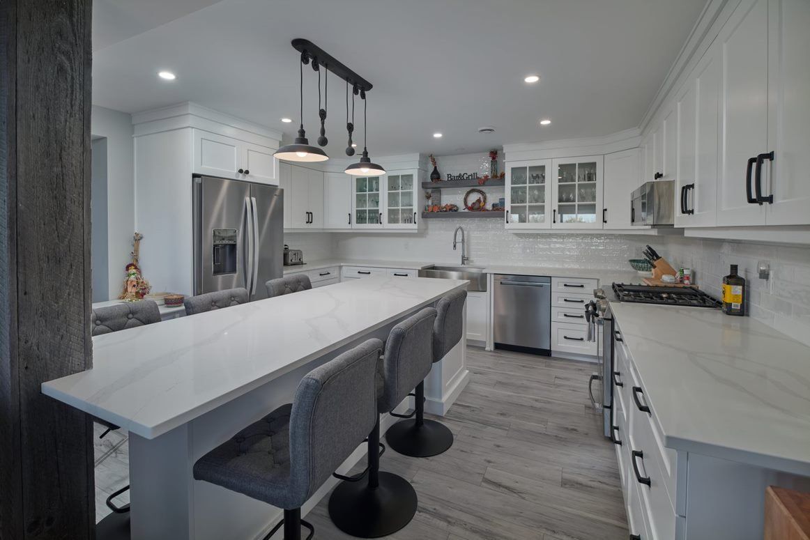 A kitchen with white cabinets and stainless steel appliances and a large island.