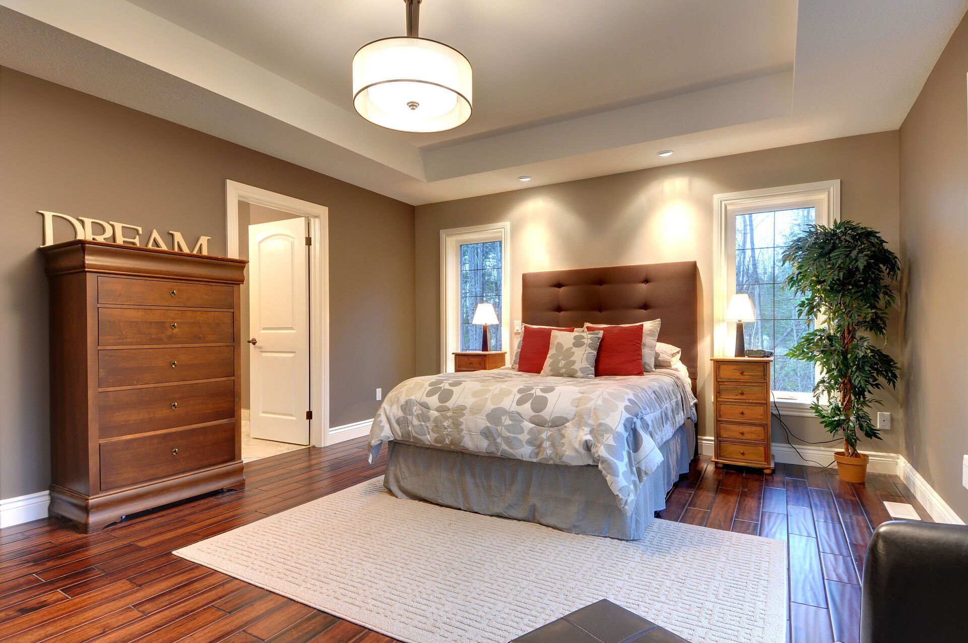 A bedroom with a bed , dresser , nightstands and a sign that says dream.
