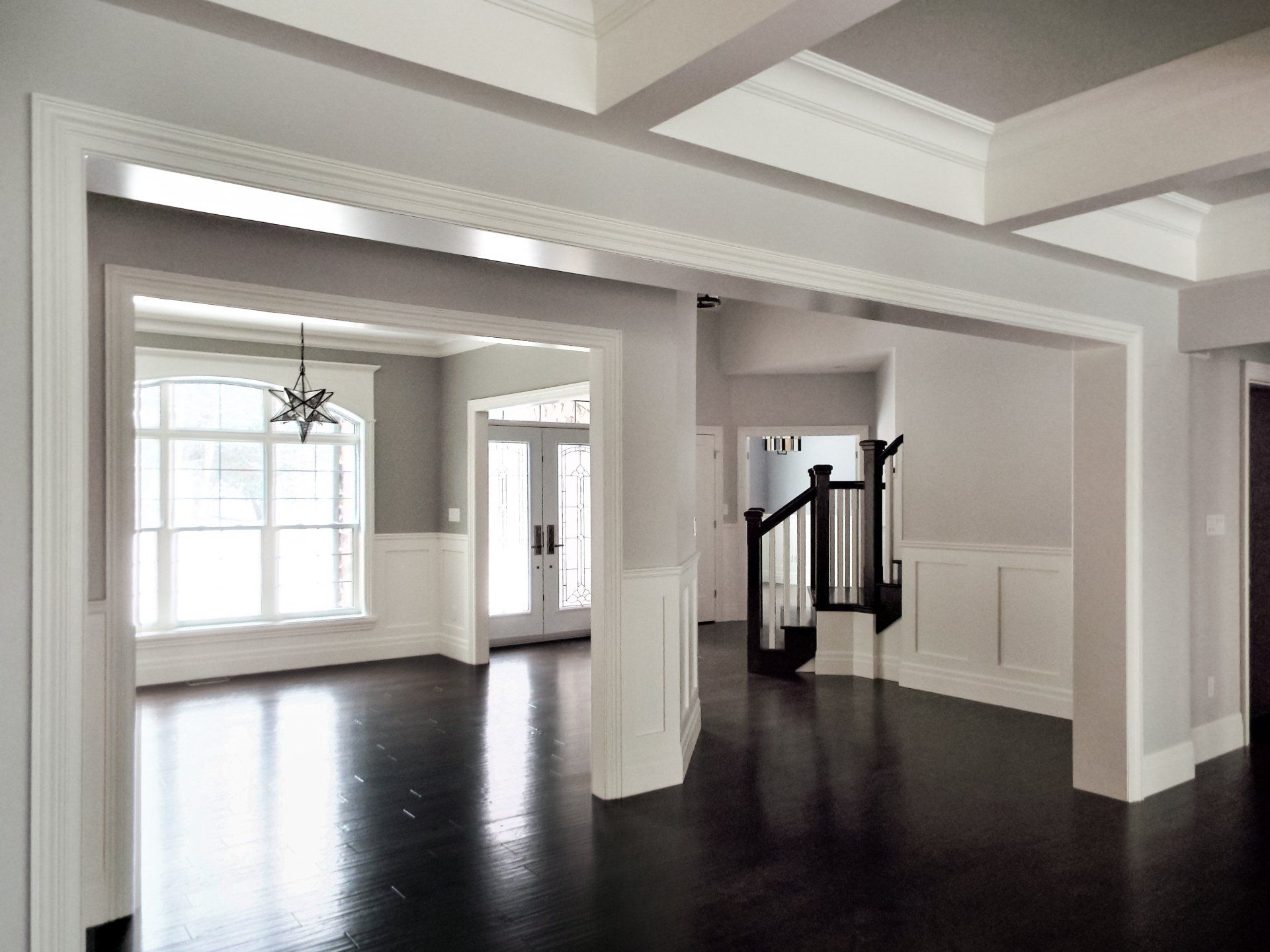 A large empty room with white walls and dark wood floors