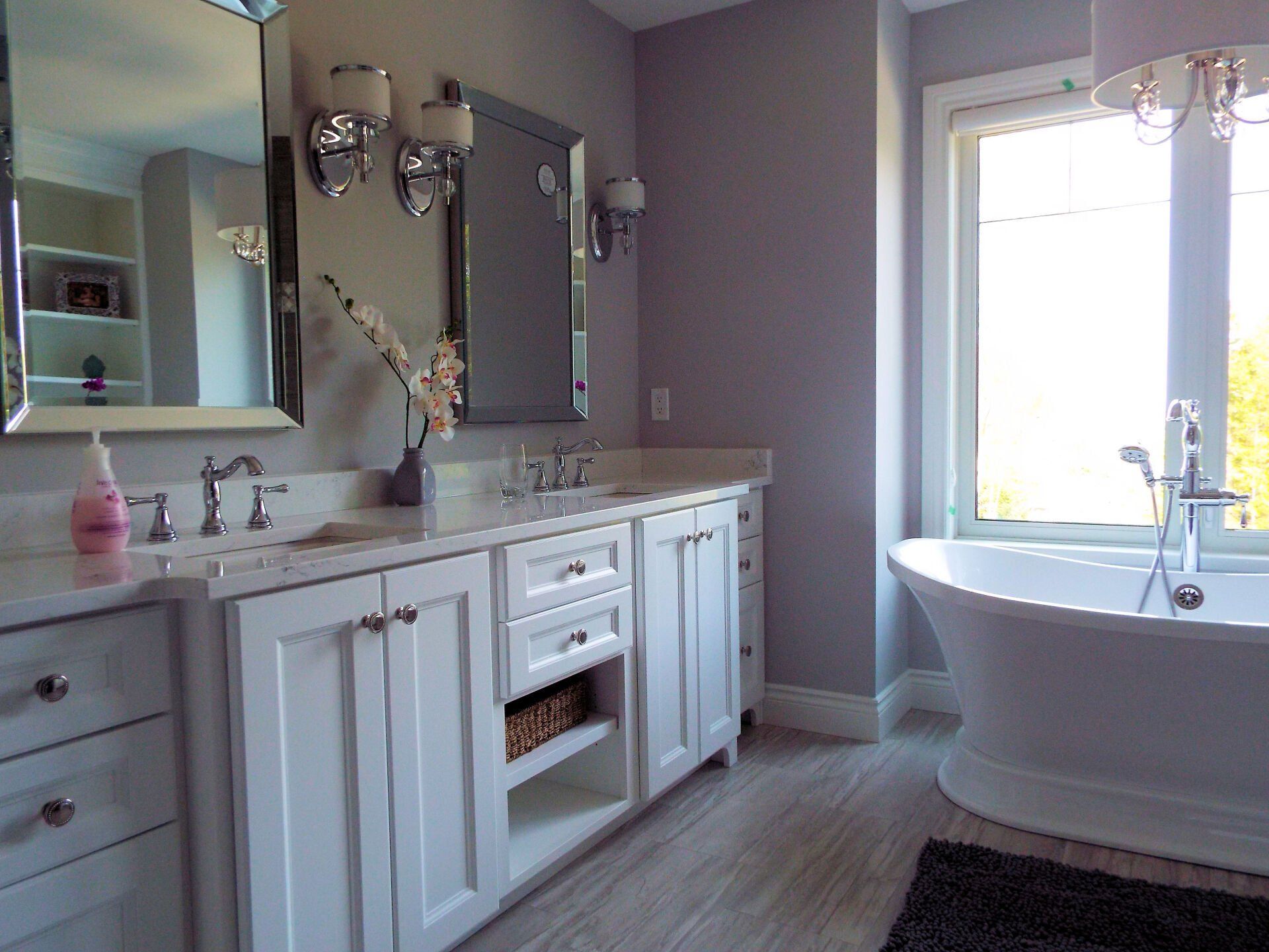 A bathroom with two sinks , a tub , a mirror and a window.