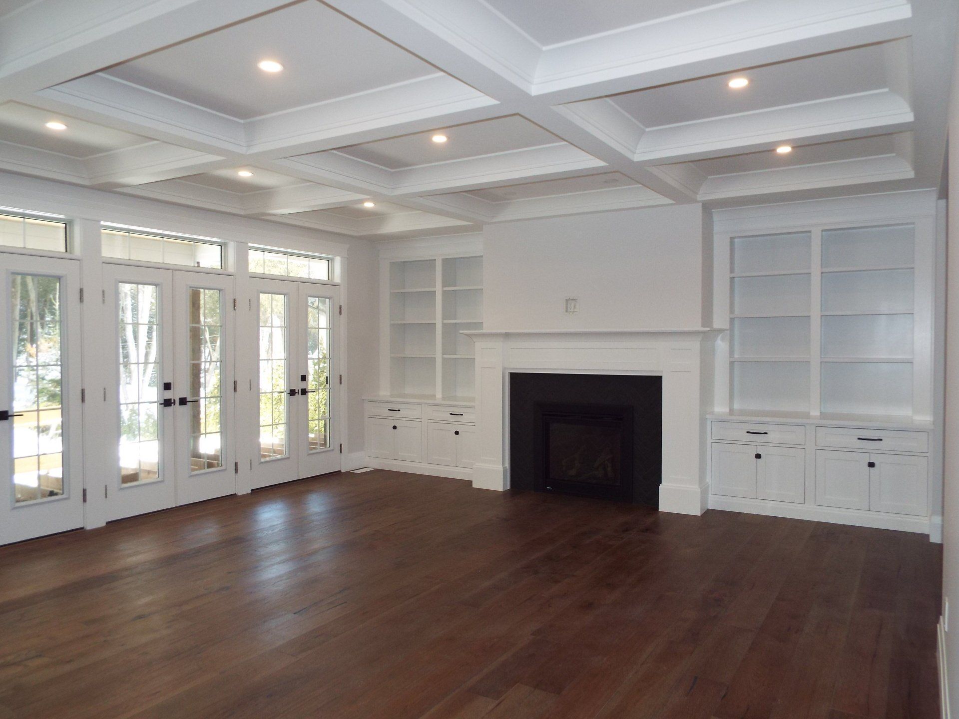 An empty living room with hardwood floors and a fireplace