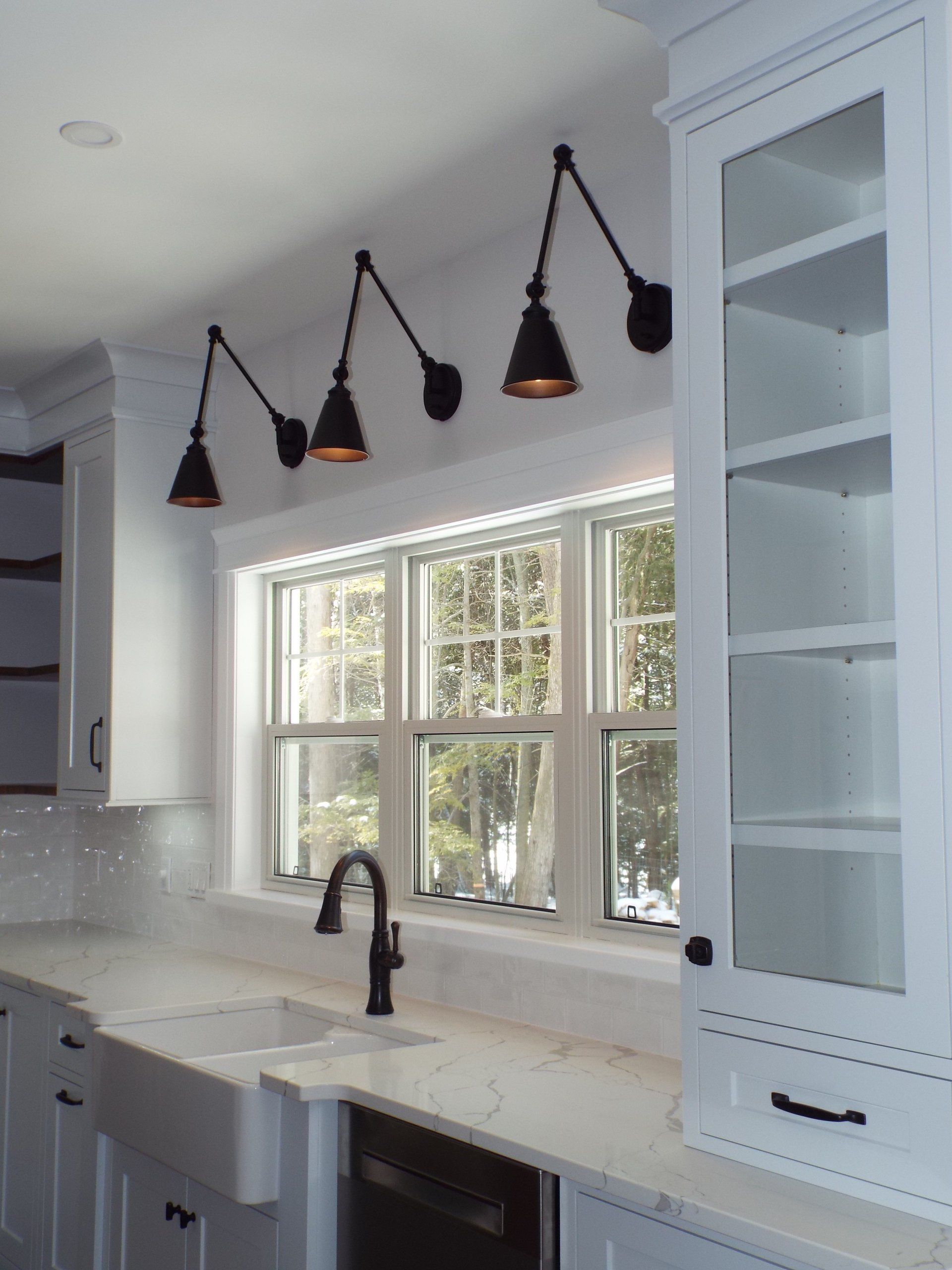 A kitchen with white cabinets a sink and a window