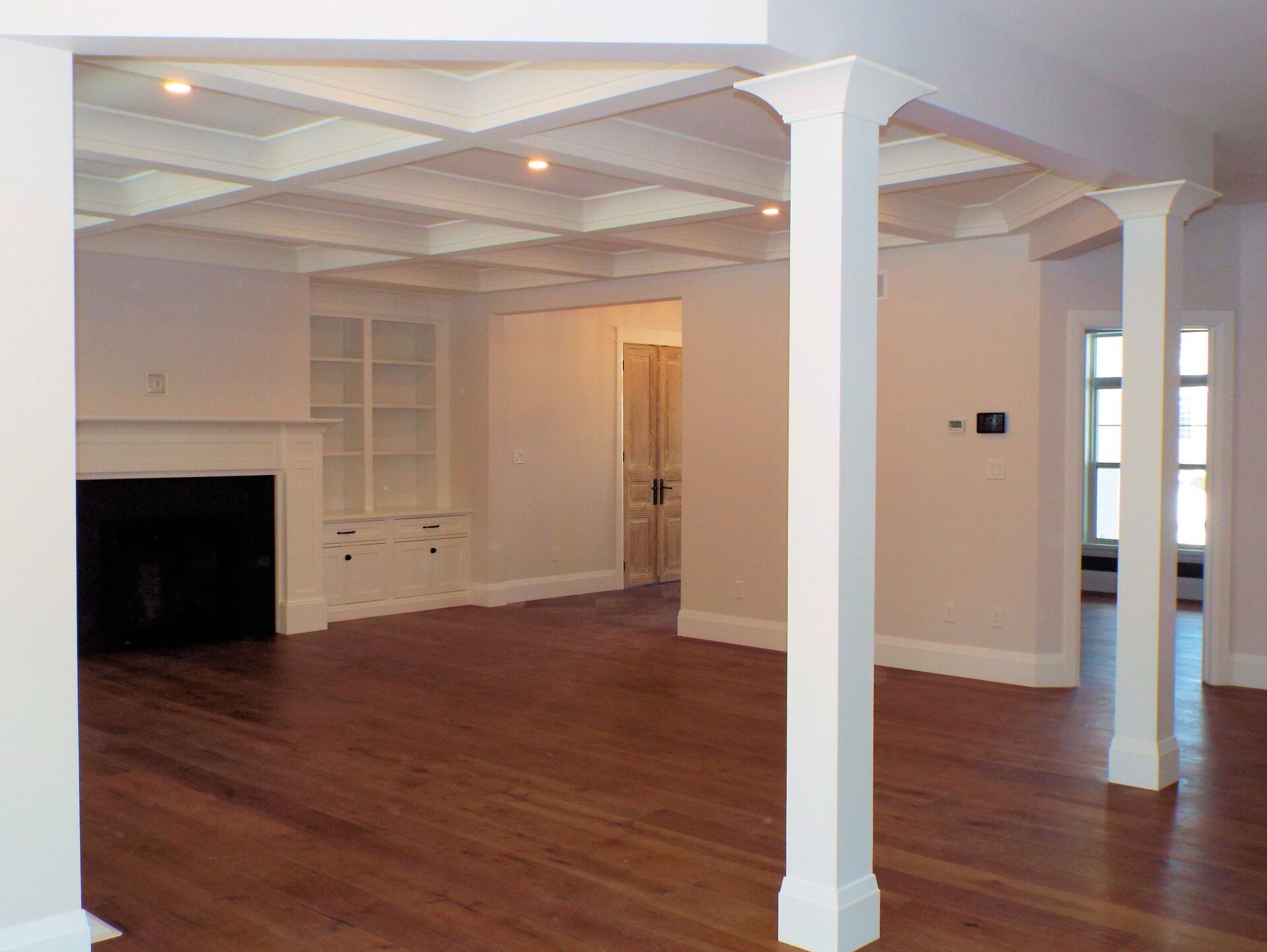 An empty living room with hardwood floors and white columns