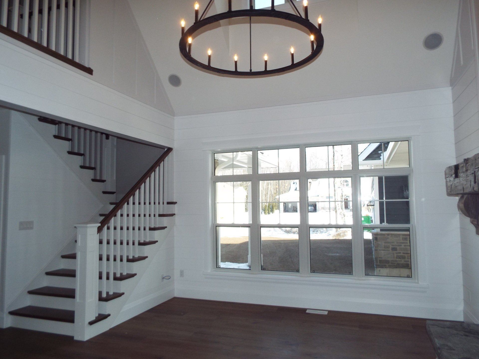 An empty room with stairs and a chandelier hanging from the ceiling