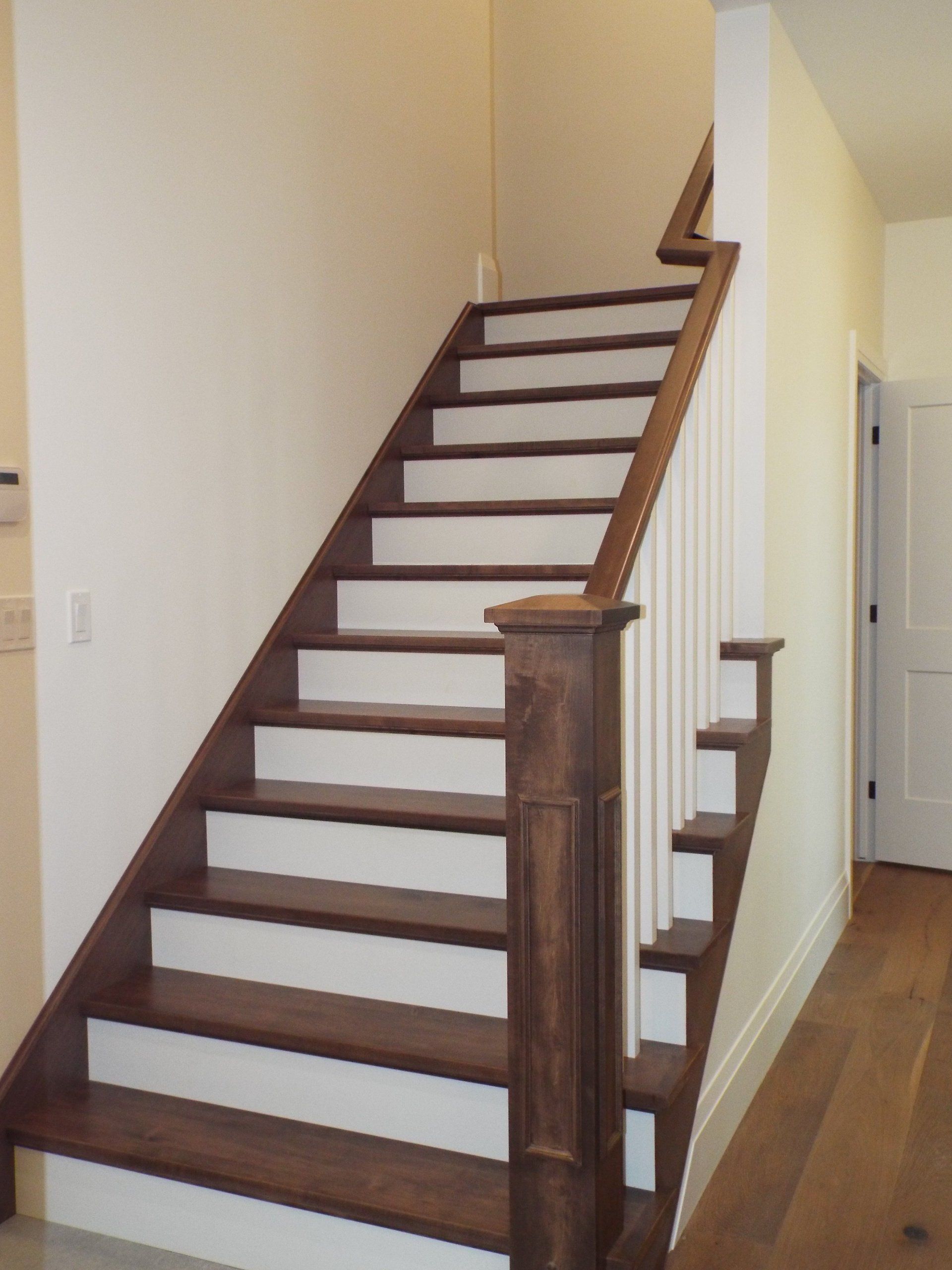 A wooden staircase with white steps in a hallway