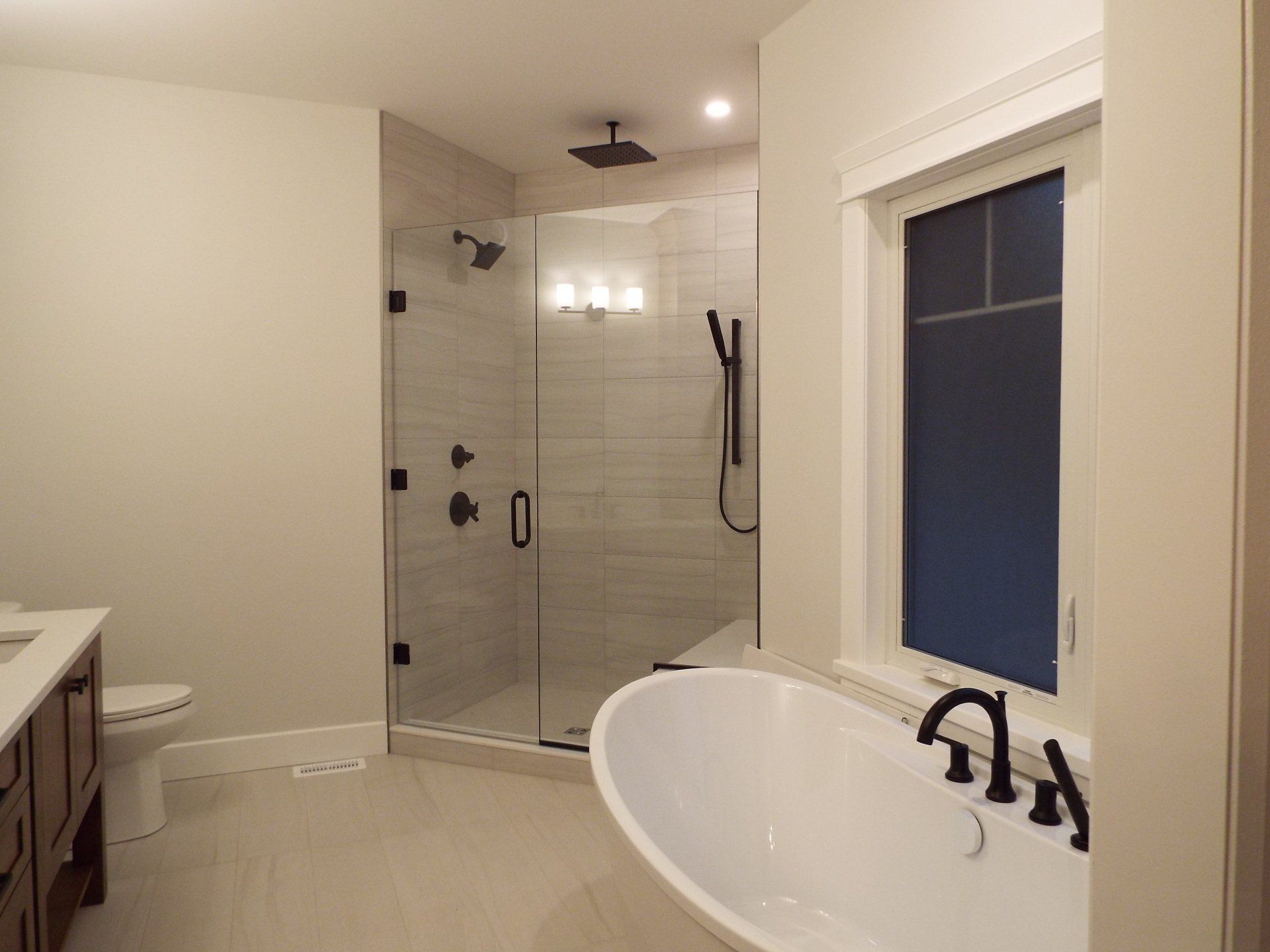 A bathroom with a tub , toilet , shower and window.
