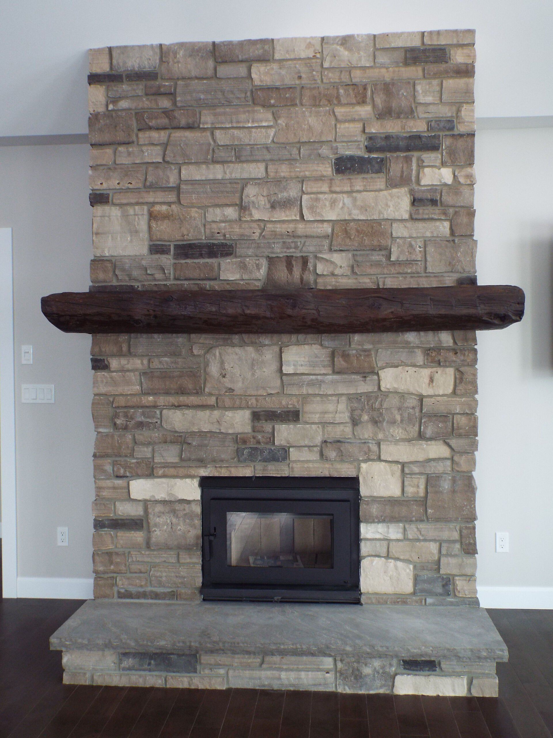 A stone fireplace with a wooden mantle in a living room