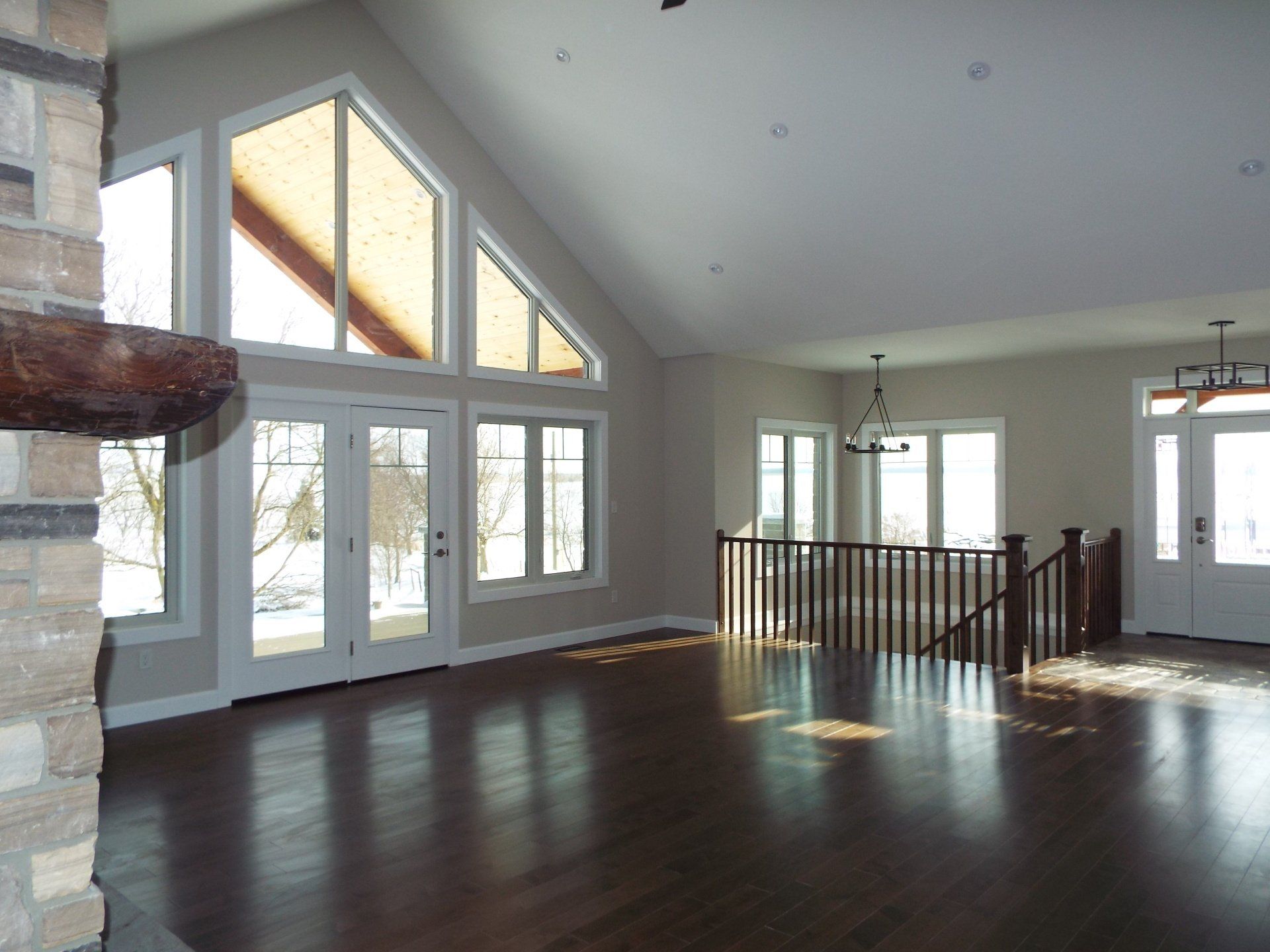 An empty living room with a vaulted ceiling and lots of windows