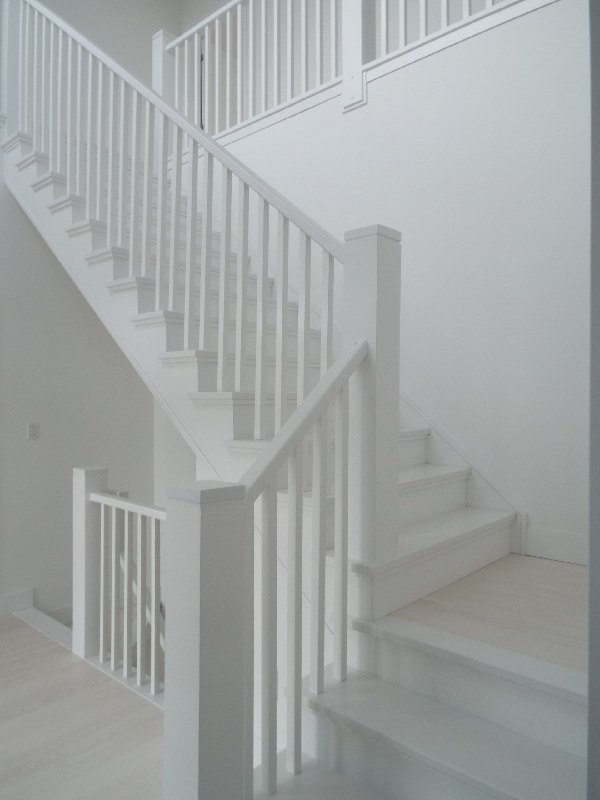 A white staircase with a white railing and steps