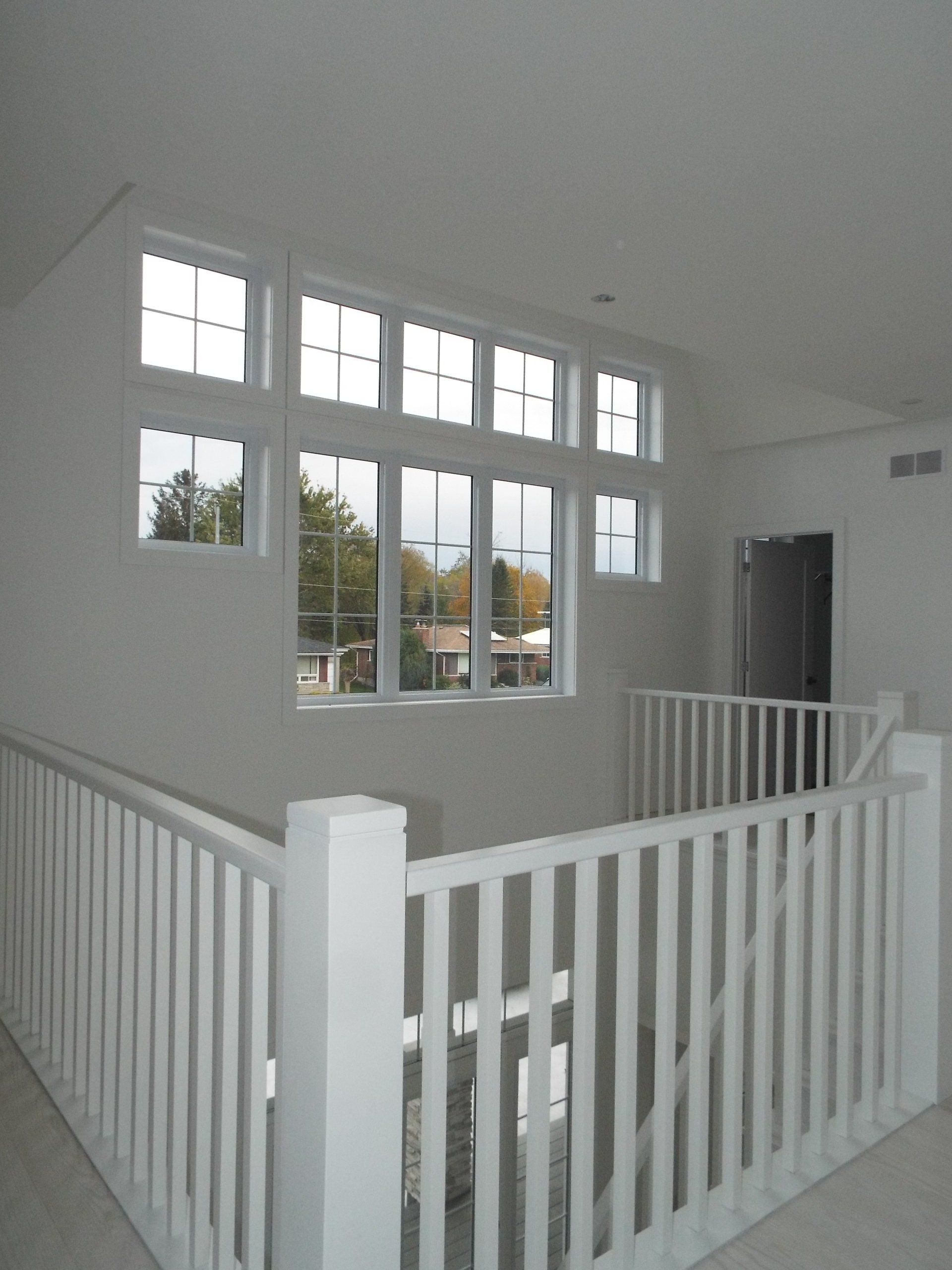 A staircase with a white railing and lots of windows