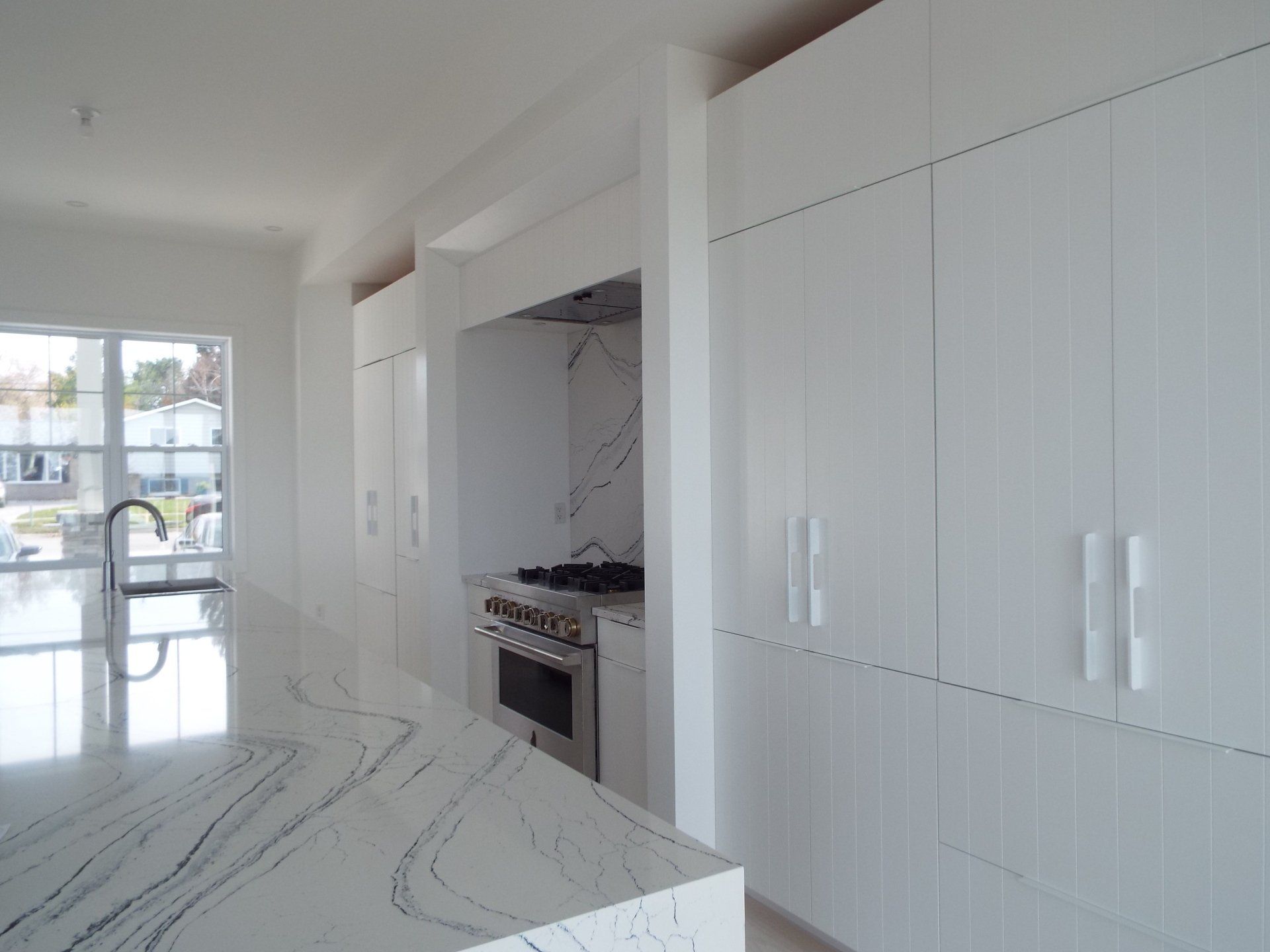 A kitchen with white cabinets , a stove , and a large island.