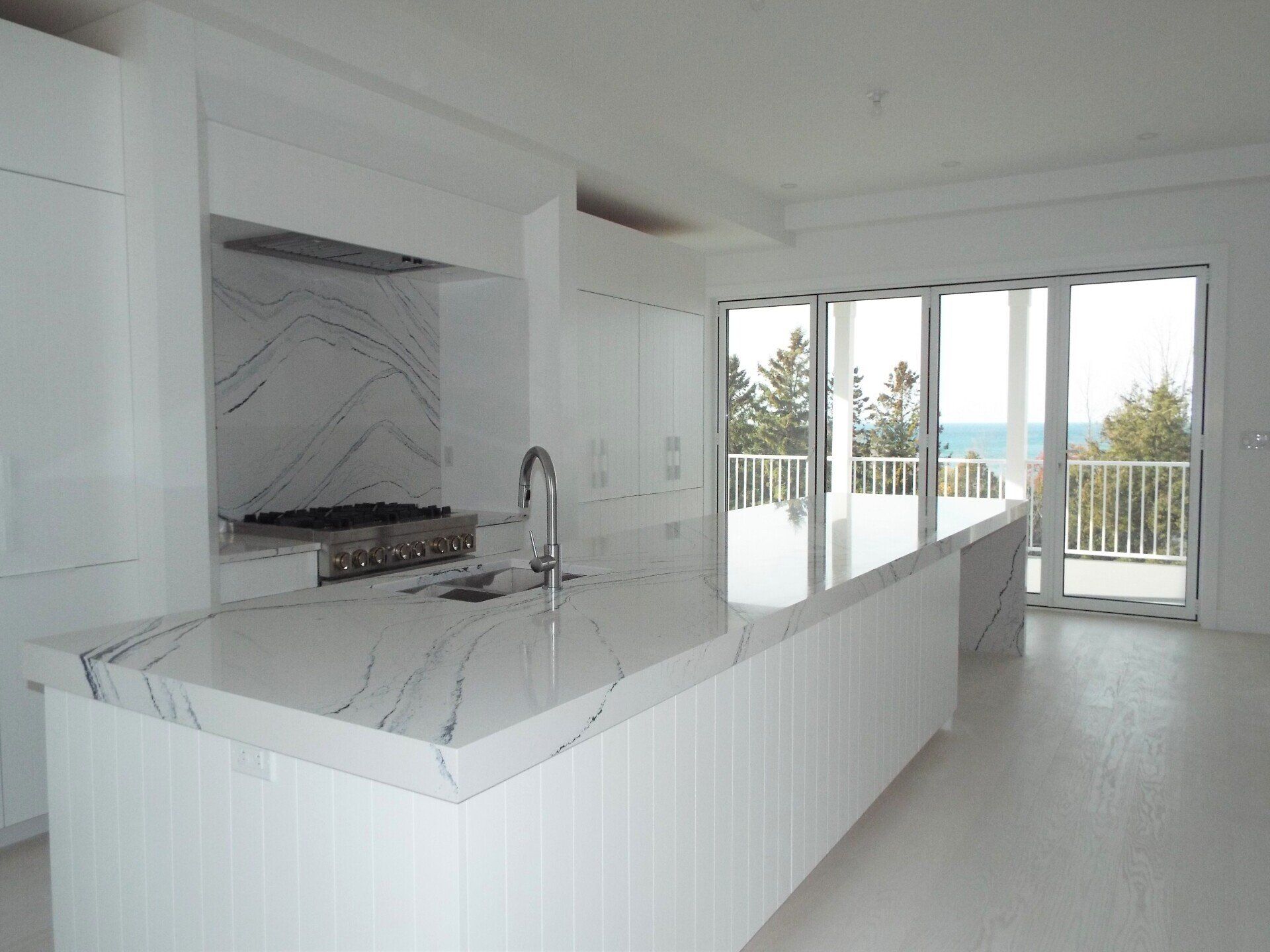 An empty kitchen with white cabinets and marble counter tops