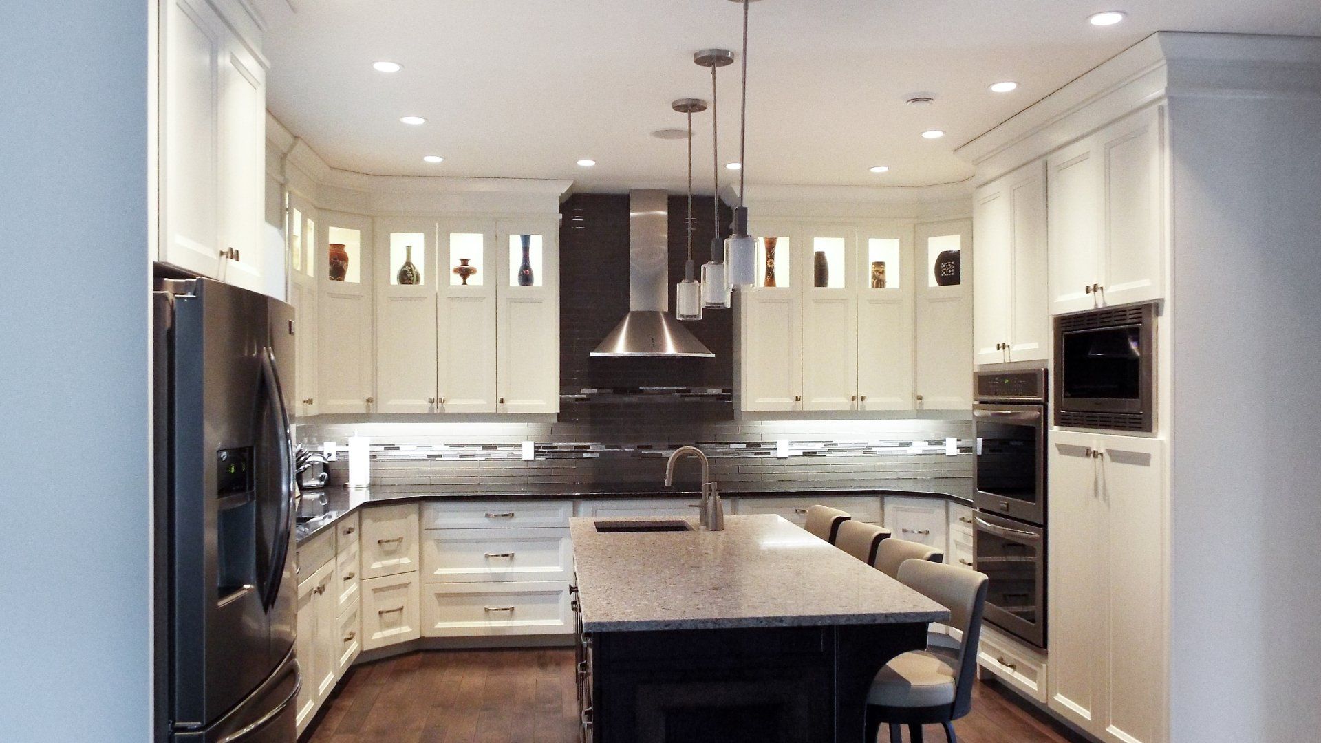A kitchen with white cabinets and black appliances and a large island