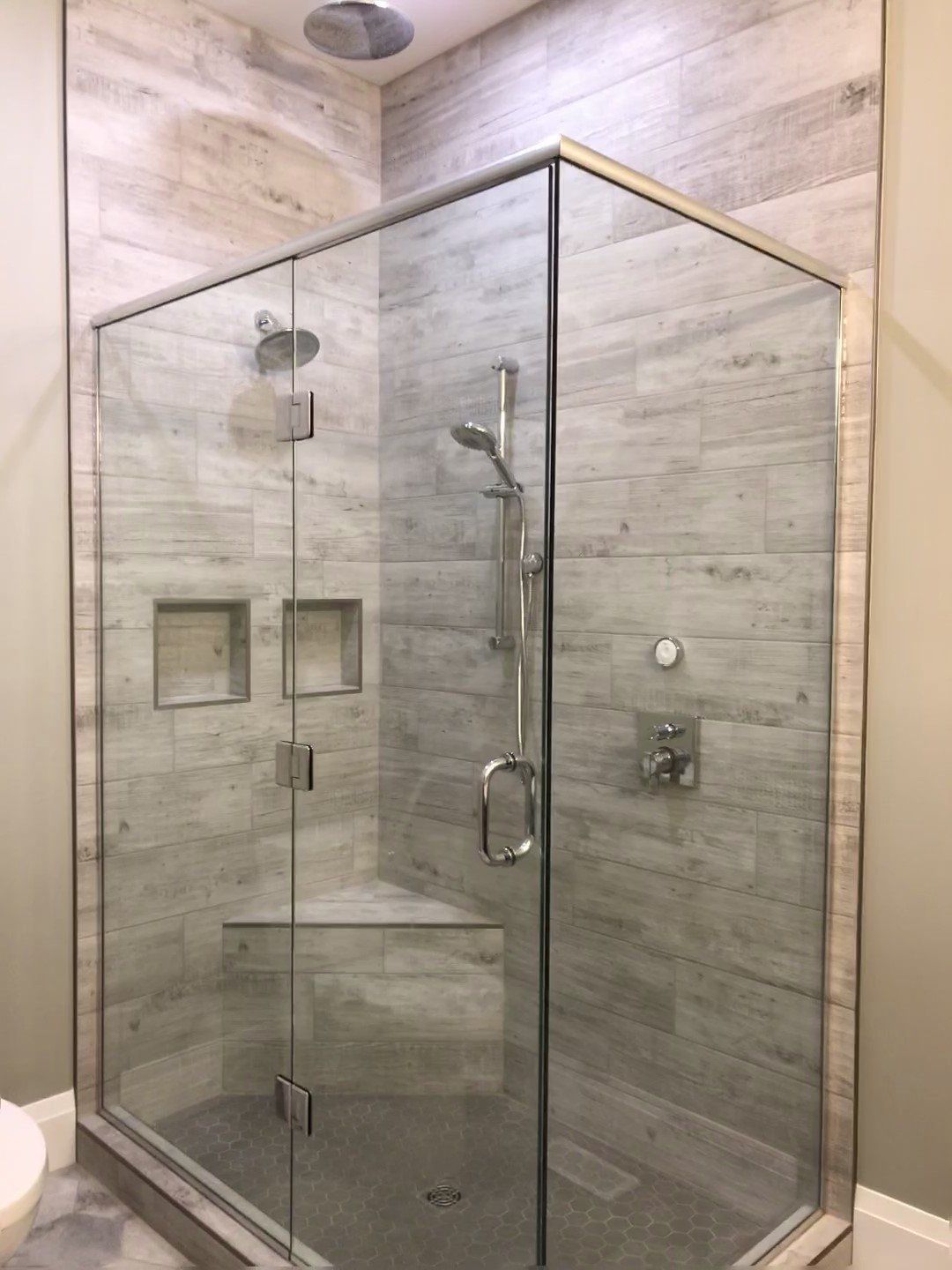 A shower stall with a glass door and a shower head in a bathroom.