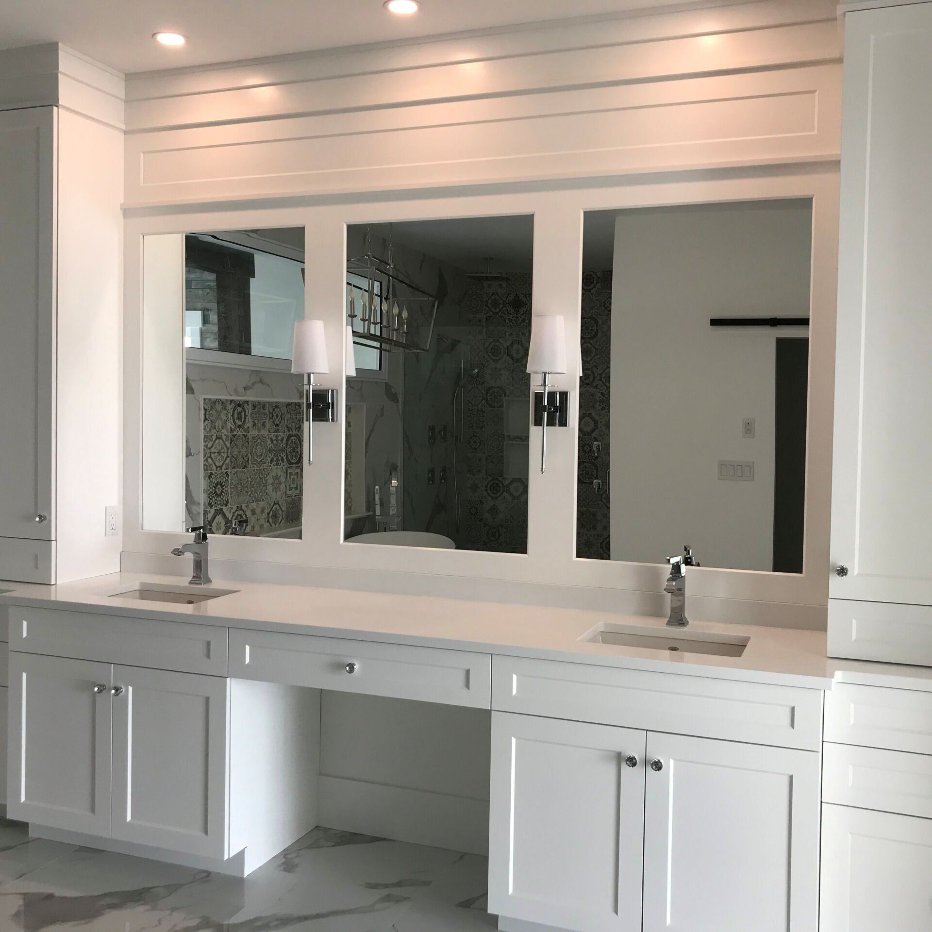 A bathroom with white cabinets and a large mirror