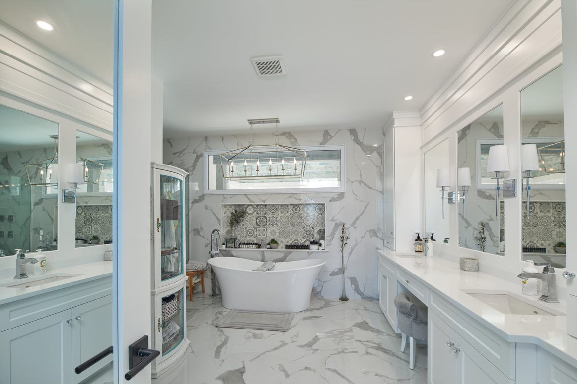 A bathroom with a tub , sinks , mirrors and a walk in shower.