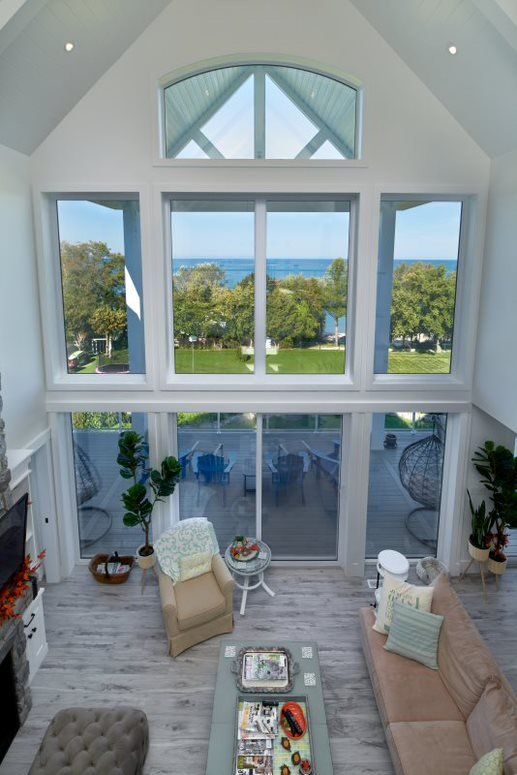 A living room with a lot of windows and a view of the ocean.