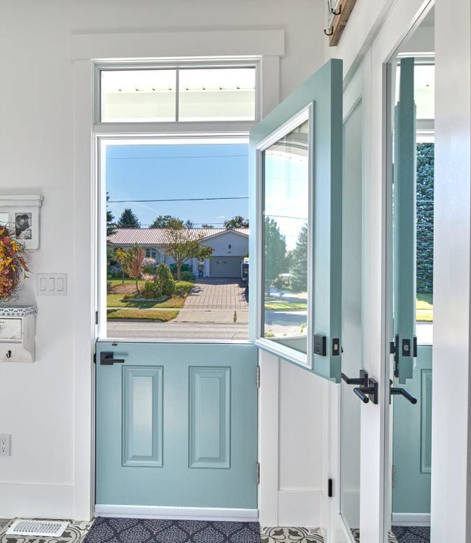 A blue door is open in a hallway with a house in the background