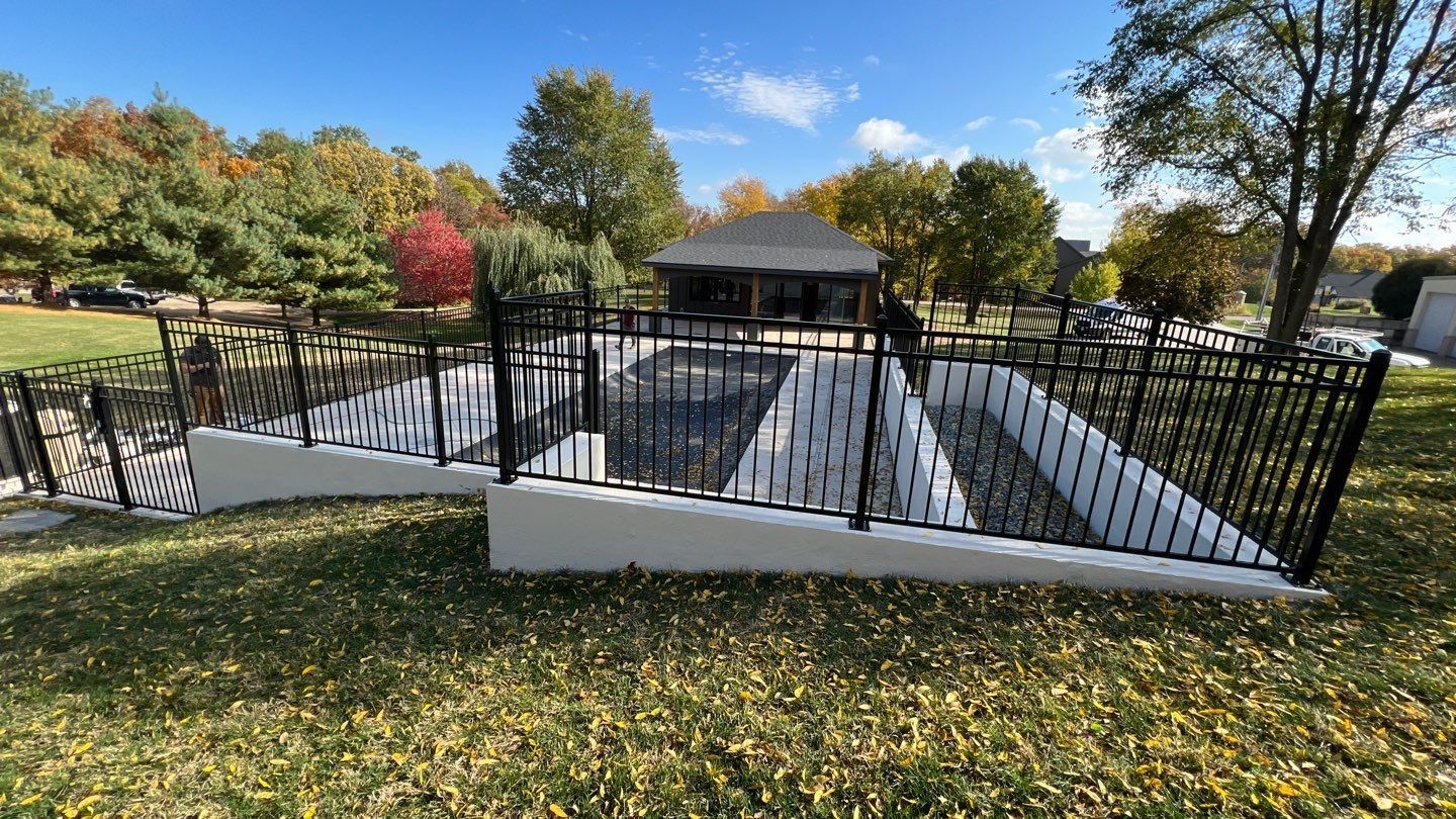 Accessible walkway with white railings leading to a gazebo in a park, surrounded by autumn trees.