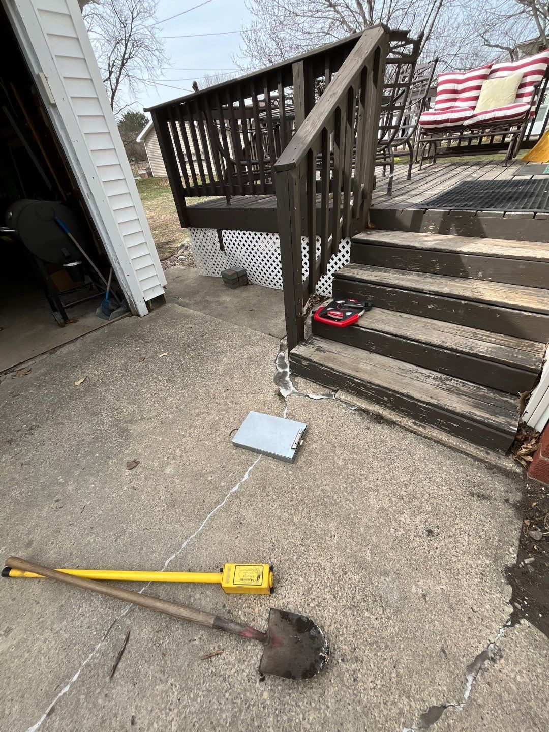 Broken concrete patio beside steps with a yellow broom and a square concrete slab on the ground